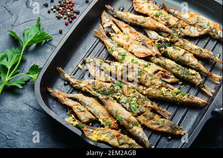 Fried capelin garnished with parsley and lemon zest in a pan Stock Photo