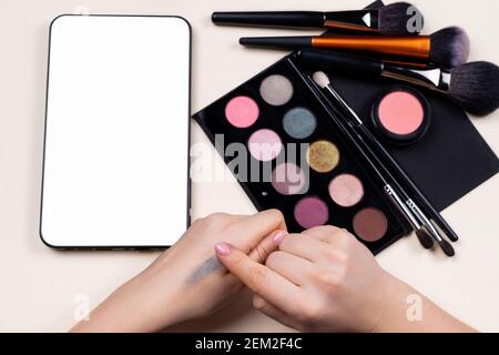 Eye shadow swatches on female hands. Colorful shadows best pigmentation. Decorative tones near blank white digital tablet screen for make up online Stock Photo