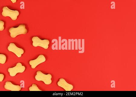 Bone shaped dog biscuits in corner of red background wih empty copy space Stock Photo