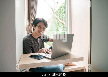 handsome asian modern man designer working home using laptop at home Stock Photo