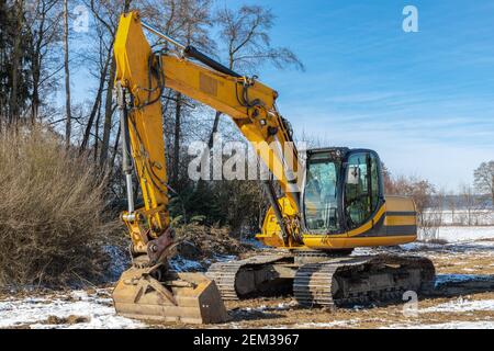 Large excavator parked on a meadow in winter Stock Photo