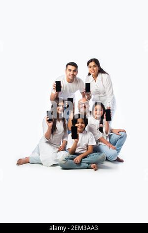 indian multigenerational family showing empty smartphone screen, sitting against white background Stock Photo