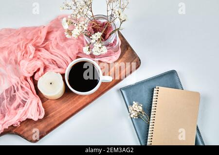 Notebooks and cup of coffee on the wooden board with flowers Stock Photo