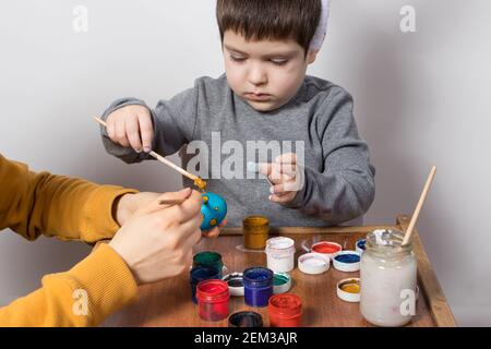 Mother and son paint chicken eggs together for the Easter holiday. Preparing for Easter. Family traditions. Stock Photo