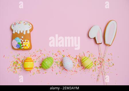 Easter cake, eggs, sugar sprinkles and cookies bunny ears on a pink background. Sweets for celebrating Easter. Stock Photo