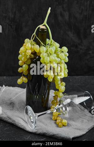 White grapes around a bottle of wine and an empty glass