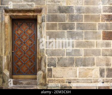 Old wooden door on background of stone wall. Stock Photo