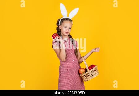 happy girl holding apples from garden. rabbit kid hold basket with fruit. child wear bunny ears. spring holiday fun. happy easter. egg hunt began. childhood happiness. Getting ready for Easter. Stock Photo