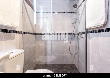 Shot of modern bathroom with a clean shower set up, towels hanging on the walls and a gimplse of the toilet seat. Stock Photo
