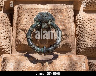A bronze lions head and ring mounted in the wall of King Charles V Palace at The Alhambra, Granada, Spain. Stock Photo