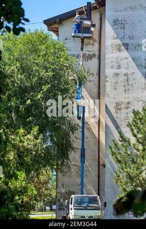 Zrenjanin, Serbia, August 13, 2020. Workers with a special truck are repairing the roof of a tall building. Roof work is very dangerous due to the hei Stock Photo
