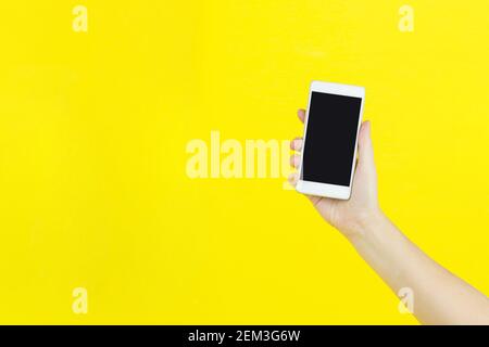 Smartphone in hand on yellow background with copy space for your text. Stock Photo