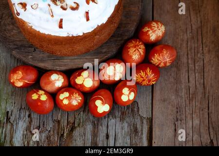 Easter cake and colored eggs. Rustic food on a wooden table. Traditional egg colored with onion peel. Clover and dill leaves pattern. Classic food for Stock Photo