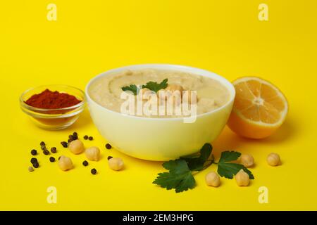 Bowl of hummus and ingredients on yellow background Stock Photo