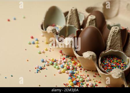 Egg box with chocolate eggs with sprinkles on beige background Stock Photo