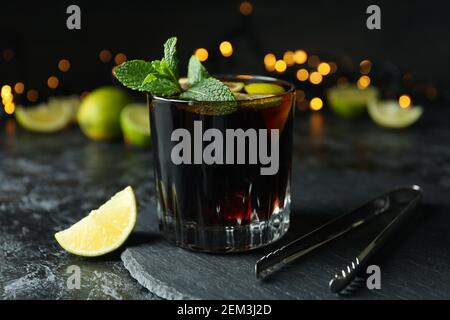 Glass of Cuba Libre cocktail against blurred lights, close up Stock Photo