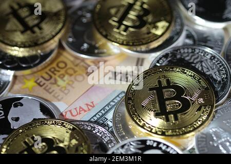In this photo illustration, visual representations of the digital cryptocurrency, Bitcoin, are arranged atop 1oz silver bullion coins and banknotes of euro, Japanese yen, Chinese yuan, and a US dollar bill on February 20, 2021 in Katwijk, Netherlands. Credit: Yuriko Nakao/AFLO/Alamy Live News Stock Photo