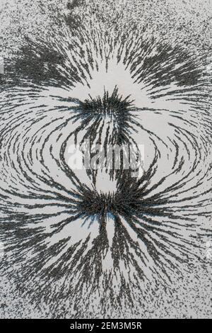 Magnetic field lines concept with bar magnet attraction and repulsion iron particles along lines of force Stock Photo