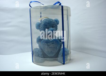Beautiful blue candle in the form of a teddy bear, handmade on a white background. Stock Photo