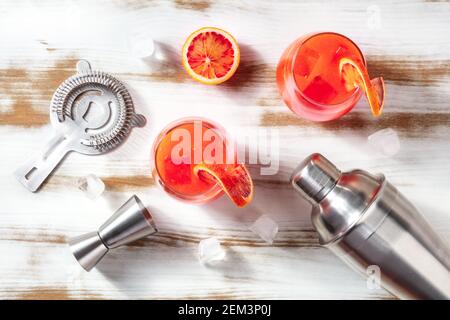 Orange cocktail with blood oranges, a shaker, a jigger, and a strainer, overhead flat lay shot Stock Photo