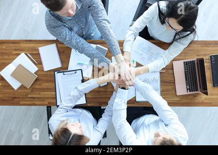 Businessmen and businesswoman at working table hold their hands together Stock Photo