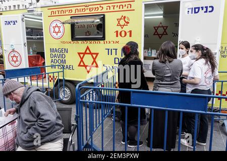 Jerusalem, Israel. 24th Feb, 2021. The IDF Home Front Command in coordination with Magen David Adom, serving as the Israeli Red Cross organization and leading EMS, make COVID-19 vaccinating more accessible to those still in denial or refusal operating a mobile vaccination station out of a caravan at Jerusalem's Shuk Mahane Yehuda Market. Credit: Nir Alon/Alamy Live News Stock Photo