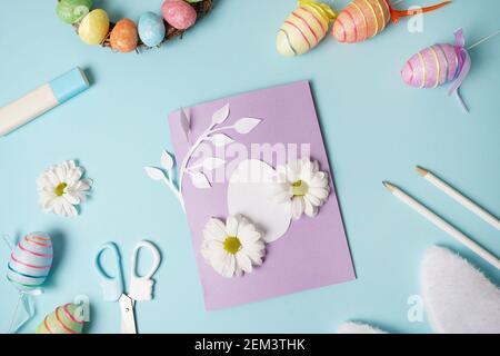 Diy Easter card from paper. greeting cards with egg on blue background. Gift idea, decor Spring, Easter. Top view. Process kid children craft. Stock Photo
