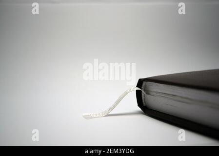 A small book, a notebook, a diary in a dark brown cover is located on a white background with interesting lighting. Stock Photo