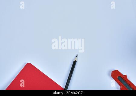 Notebook, utility knife and pencil on blue background Stock Photo