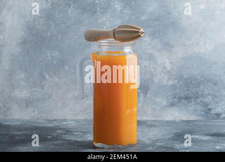 Orange juice in a glass pitcher with a wooden reamer Stock Photo