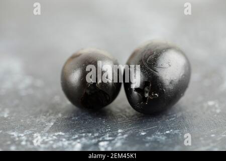 Two black olive fruits on a marble background Stock Photo