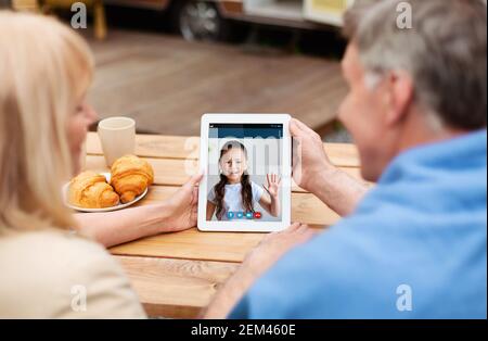 Grandparents making video call with kid using tablet Stock Photo