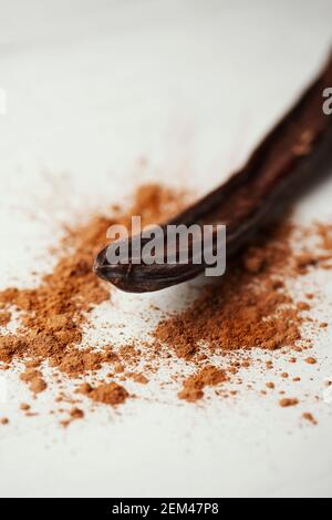 closeup of a ripe carob pod and some carob powder sprinkled on a white table Stock Photo