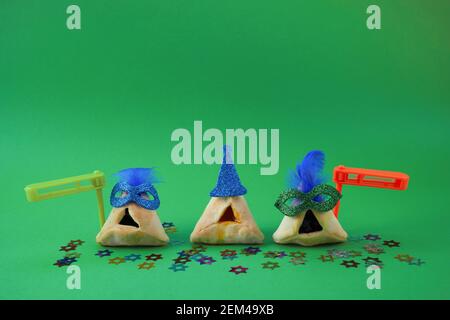 Purim celebration concept. Traditional Hamantashen cookies with clown hat and gragger. Stock Photo