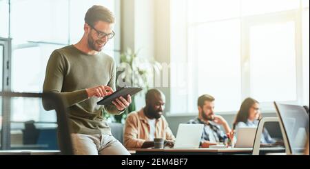 Joyous young gentleman using his tablet for work Stock Photo