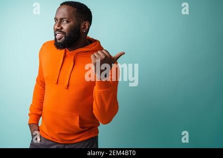 Happy african american man smiling and pointing finger aside isolated over blue background Stock Photo