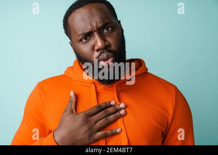 Surprised african american man looking at camera and holding hand on her chest isolated over blue background Stock Photo