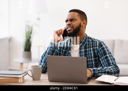Discontented Black Businessman Talking On Cellphone Discussing Bad News Indoor Stock Photo