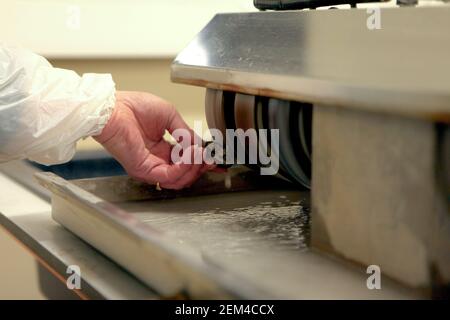 Laboratory worker polishing boulder precious stone. worker hands, no face, unrecognizable person. worker cutting a stone Stock Photo