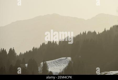 Garmisch Partenkirchen, Germany. 24th Feb, 2021. The sky above the mountains in the Wetterstein range is clouded by the Sahara sand in the air. Dust from the African desert colours the sky yellowish and creates a special light atmosphere. Credit: Angelika Warmuth/dpa/Alamy Live News
