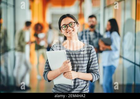 Excited young woman posint with other people in background Stock Photo