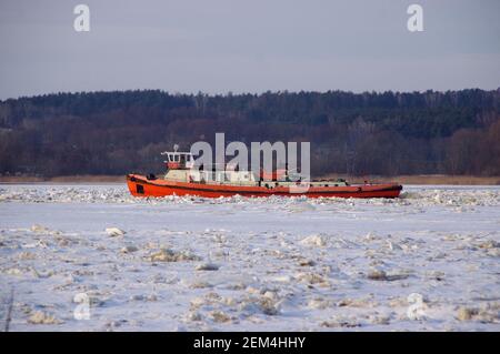 Icebreaker in operation in the winter season. Breaking ice floes on the river. Stock Photo
