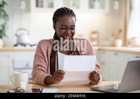 Overjoyed Black Woman Reading Letter In Kitchen And Exclaiming With Excitement Stock Photo