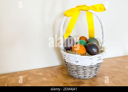Still life of marbled coloured Easter eggs in willow basket with yellow ribbon Stock Photo