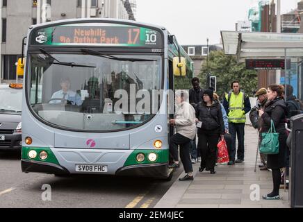 Pasengers board a single decker First bus at a stop in the city centre of Aberdeen, Scotland Stock Photo