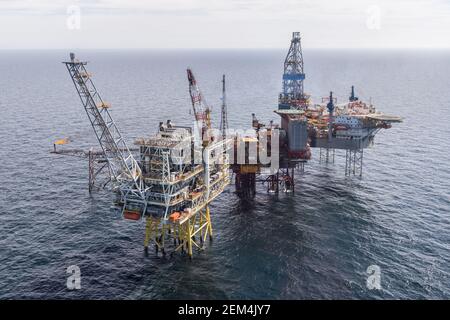 Offshore oil installation or rig with jack up drilling rig alongside Stock Photo