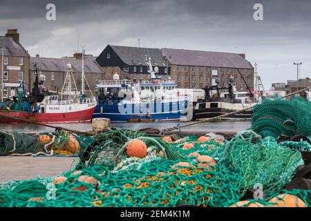 Fishing nets and gear in front of trawlers at Peterhead harbour in Aberdeenshire, Scotland, UK Stock Photo