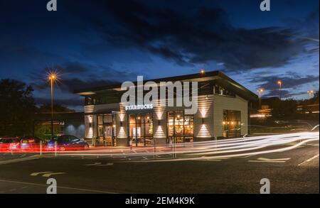 A busy Starbucks coffee restauarant and take away with traffic light trails at night Stock Photo