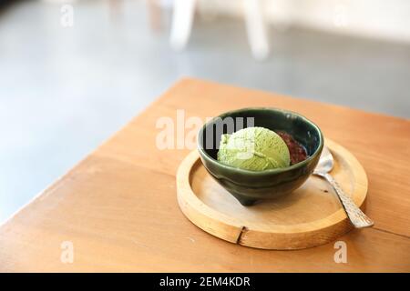 Japanese green tea ice cream with red bean topping on wooden table in coffee shop Stock Photo