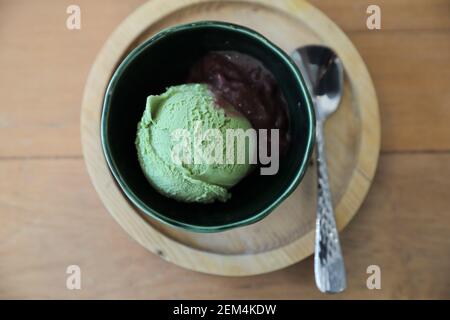 Japanese green tea ice cream with red bean topping on wooden table in coffee shop Stock Photo